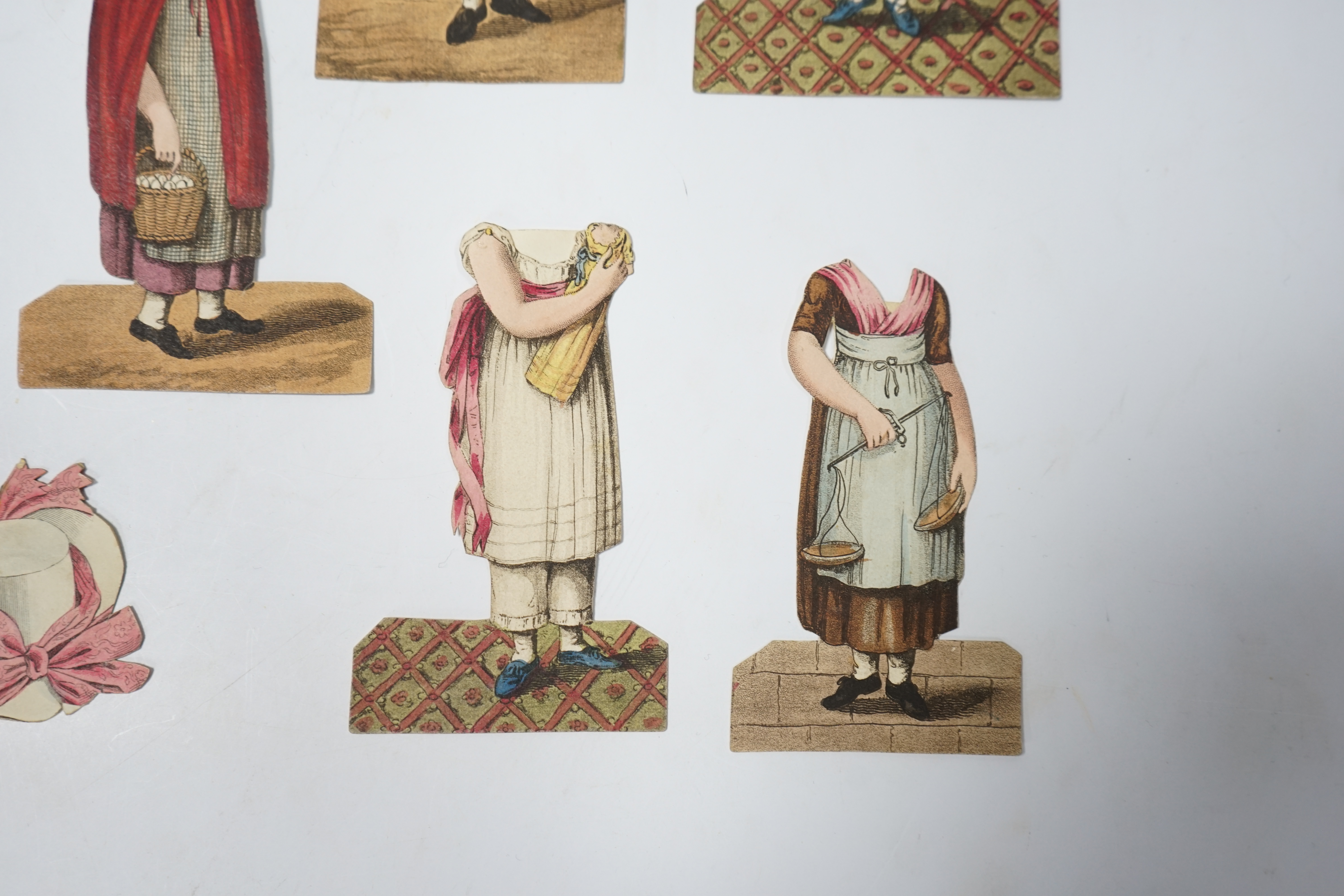 An early 19th century boxed Rudolph Ackermann La Poupee-Modele paper doll set, comprising of a double sided doll in lingerie with mahogany stand, six double sided gowns and four bonnets, together with eight similar figur